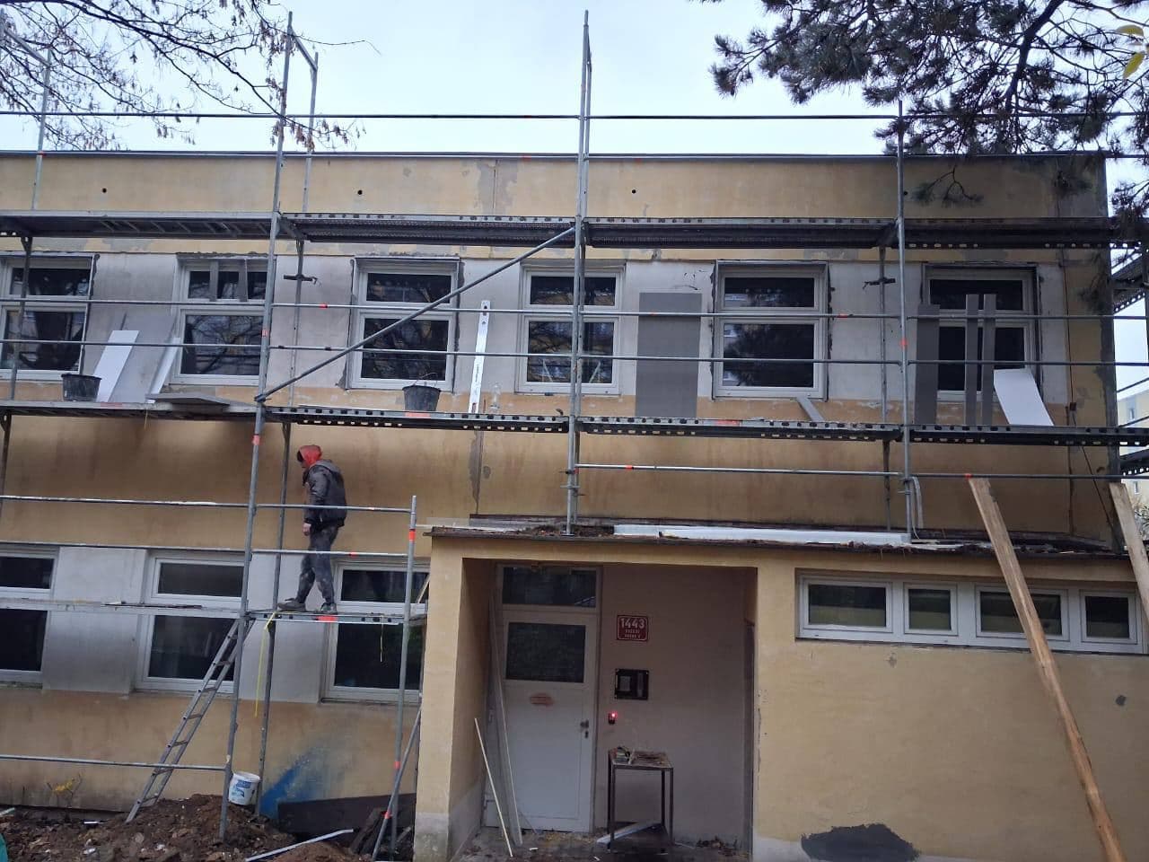 Pracovník na lešení připravuje ostění oken horního podlaží