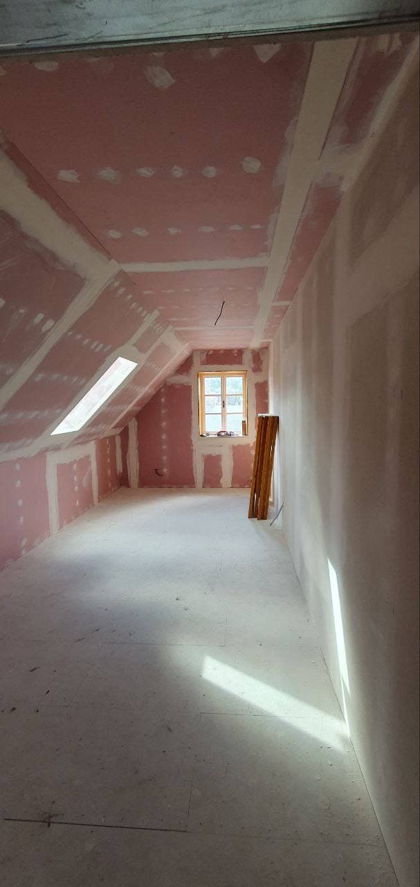 Dlouhý podkrovní prostor po opláštění sádrokartonem.